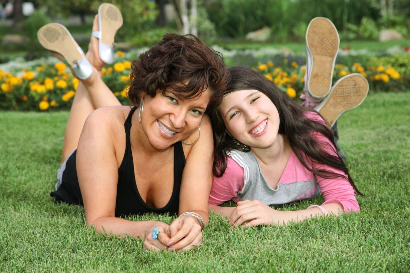 mother and daughter lie on the grass and smile